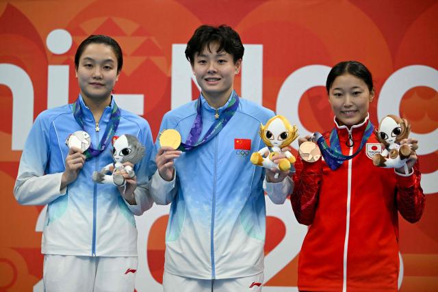 Silver medallist China's Chen Jia (L), gold medallist China's Chen Yiwen (C) and bronze medallist Japan's Sayaka Mikami (R) pose on the podium during the victory ceremony of the women's 3m springboard final diving event during the 2026 Asian Games at the Tokyo Aquatics Centre in Tokyo on September 30, 2026. (Photo by ANDREW CABALLERO-REYNOLDS / AFP)