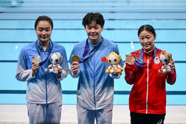 Silver medallist China's Chen Jia (L), gold medallist China's Chen Yiwen (C) and bronze medallist Japan's Sayaka Mikami (R) pose following the victory ceremony of the women's 3m springboard final diving event during the 2026 Asian Games at the Tokyo Aquatics Centre in Tokyo on September 30, 2026. (Photo by ANDREW CABALLERO-REYNOLDS / AFP)