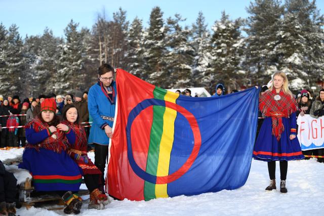 (FILES) Members of the Sami community hold a Sami flag before marching during a Friday for Future protest in Jokkmokk, northern Sweden on February 7, 2020 on the Sami National Day. A Swedish truth commission on September 30, 2026 urged the state to apologise for injustices committed against its indigenous Sami people, including assimilation programmes, and provide compensation and redress. The Truth Commission for the Sami People said it would present 71 proposals to the government, authorities, museums and Church of Sweden "to acknowledge and take responsibility, compensate for the human rights of the Sami people and find a way forward based on equality and respect for the human rights of the Sami people". (Photo by Jonathan NACKSTRAND / AFP)