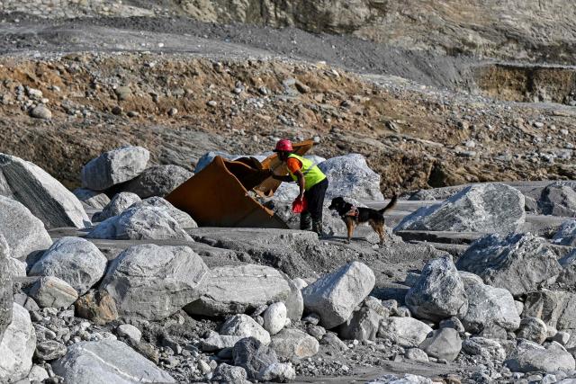 A search and rescue team member, along with a sniffer dog, looks for victims following the August 26 flash flood, on the bank of the Trishuli River in Nepal's Nuwakot district on September 30, 2026. (Photo by Prakash MATHEMA / AFP)