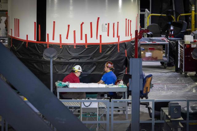 Workers are seen next to a solid rocket booster of the Space Launch System (SLS) for Artemis III are seen inside the Vehicle Assembly Building (VAB) at Kennedy Space Center, in Cape Canaveral, Florida, on September 30, 2026. Artemis III is an upcoming crewed mission led by the NASA Artemis program, targeting a 2027 launch. (Photo by Marco BELLO / AFP)