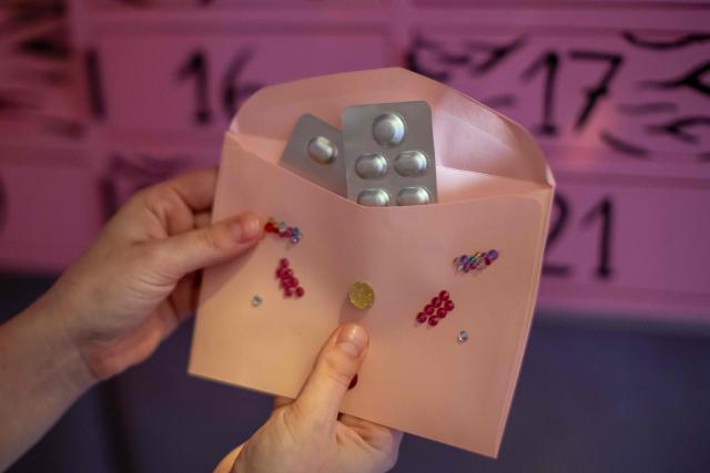 This photo, taken on September 30, 2026, shows an activist presenting an envelope containing medication from one of the compartments of the “Abortomat” – Poland’s first-ever abortion locker that allows women to access pregnancy-terminating pills anonymously, at the abortion consultation point “Abotak,” located across the street from the entrance to the Polish parliament in Warsaw. Polish activists have opened the country's first-ever abortion locker, allowing women to access pregnancy-terminating pills anonymously and immediately in the country with some of Europe's strictest abortion laws, an activist told AFP on September 30, 2026. (Photo by Wojtek RADWANSKI / AFP)