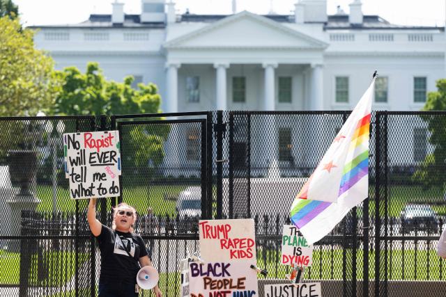 A demonstrator holds a sign at Lafayette Park near the White House in Washington, DC, September 30, 2026, following a partial re-opening of the park after a renovation. (Photo by SAUL LOEB / AFP)
