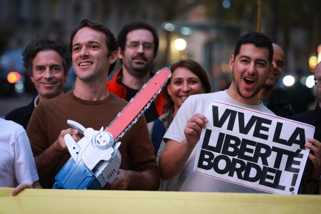 Protesters hold a chainsaw and placard reading "Long live freedom!" as they take part in a rally in support of Argentine President Javier Milei at the start of his visit to France, in Paris, on September 30, 2026. The ultra-liberal president is in Paris to October 2 oversee the "Argentina Week" forum, aimed at luring investment in Argentina. (Photo by Kenzo TRIBOUILLARD / AFP)