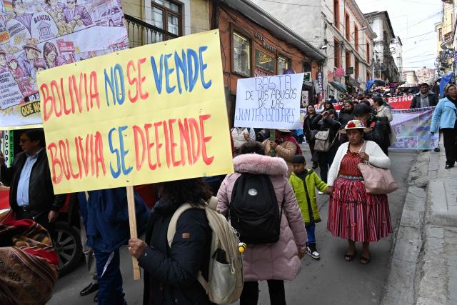 A demonstrator holds a sign reading "Bolivia is not for sale, Bolivia must be defended" during a protest march by education workers in La Paz, Bolivia, on September 30, 2026. Teachers are demanding wage increases in line with the rising cost of the basic food basket and the repeal of decrees that, according to their union, have affected their economic situation. (Photo by Aizar RALDES / AFP)