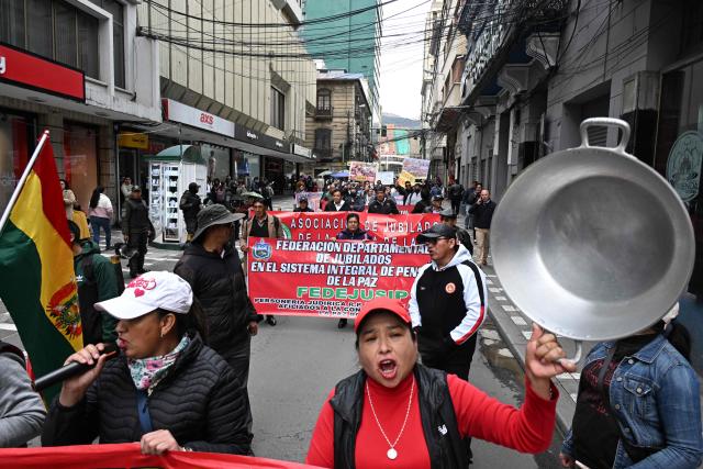 A demonstrator raises an empty cooking pot during a protest march by education workers in La Paz, Bolivia, on September 30, 2026. Teachers are demanding wage increases in line with the rising cost of the basic food basket and the repeal of decrees that, according to their union, have affected their economic situation. (Photo by Aizar RALDES / AFP)