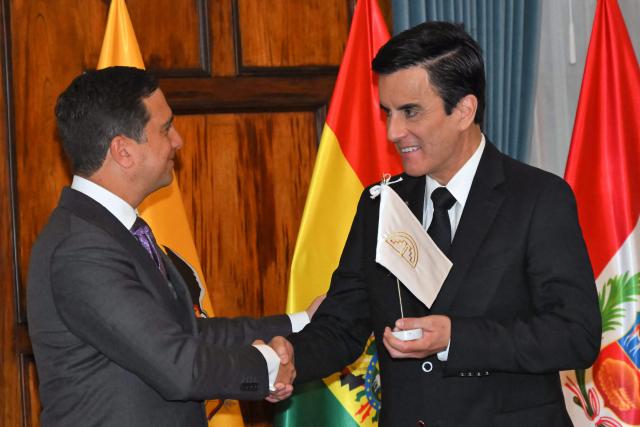 Ecuadorian Foreign Minister Roberto Kury (L) hands over the flag of the Andean Community (CAN) to his Peruvian counterpart, Carlos Espa, during the transfer of the bloc's rotating presidency at the Foreign Ministry in Quito on September 30, 2026. (Photo by Rodrigo BUENDIA / AFP)
