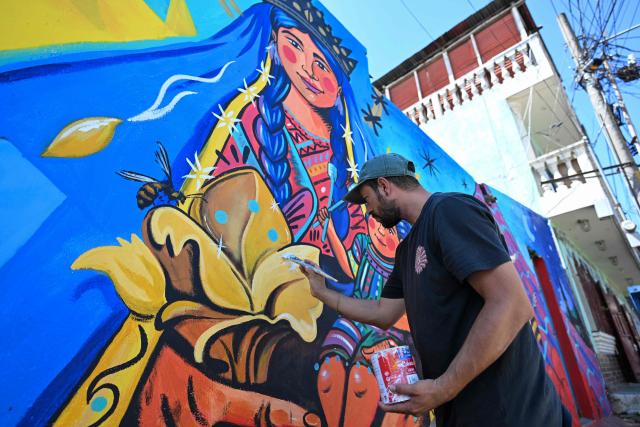 Guatemalan artist Luis Fernando Izquierdo retouches his mural of the Virgin Mary and the child Jesus on the streets of Santa Marнa de Jesъs, Guatemala on September 30, 2026. The murals are part of “"A New Air for Santa Maria de Jesus" an initiative that seeks to restore deteriorated spaces and strengthen the identity of this community through art. (Photo by Johan ORDONEZ / AFP)