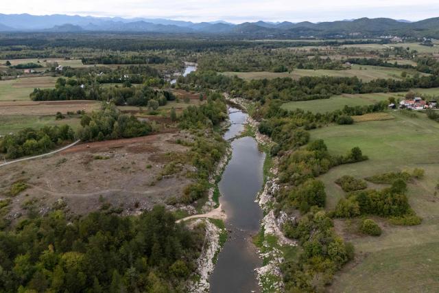 A aerial view shows the Lika River flowing through Gospic, Croatia's Lika region, on September 21, 2026. As Croatia prepares to clean up tens of thousands of tonnes of hazardous waste dumped in the heart of its idyllic Lika region, locals fear years of illegal dumping may have spread into its pristine surrounds. (Photo by MARKO PERKOV / AFP)