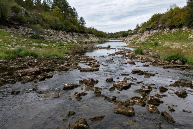 A aerial view shows the Lika River flowing through Gospic, Croatia's Lika region, on September 21, 2026. As Croatia prepares to clean up tens of thousands of tonnes of hazardous waste dumped in the heart of its idyllic Lika region, locals fear years of illegal dumping may have spread into its pristine surrounds. (Photo by MARKO PERKOV / AFP)