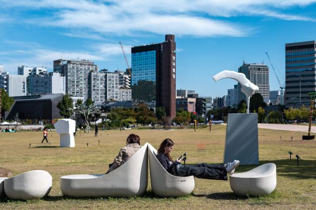 People rest at Yeolrin Songhyeon Green Square in Seoul on October 1, 2026. (Photo by Philip FONG / AFP)
