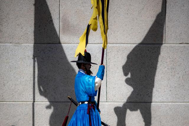 A performer in traditional guard uniform takes part in a re-enactment of a royal guard changing ceremony at Gyeongbokgung Palace in Seoul on October 1, 2026. (Photo by Philip FONG / AFP)