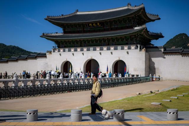 A man walks with a dog outside Gwanghwamun gate of the Gyeongbokgung Palace in Seoul on October 1, 2026. (Photo by Philip FONG / AFP)