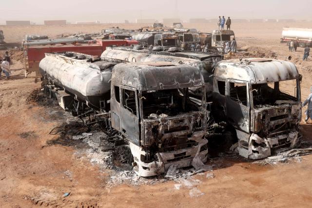 Men stand above the wreckage of fuel tankers following a fire at the Islam Qala border crossing in western Afghanistan's Herat province on October 1, 2026. (Photo by Mohsen KARIMI / AFP)