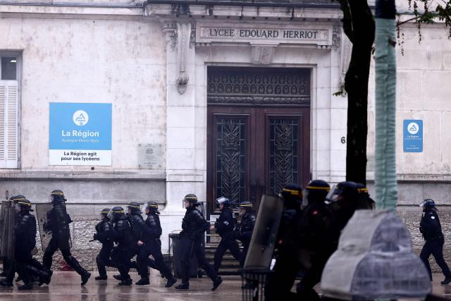 French Republican Security Corps (CRS - Compagnies Republicaines de Securite) run past the Lycee Edouard Herriot secondary school during ongoing protest action by students calling for the hiring of substitute teachers, increased resources, and decent learning conditions, in Lyon, central eastern France, on October 1, 2026. Since late September, students have staged protests outside schools over grievances ranging from timetables, class sizes and a shortage of teachers to overheated classrooms during this year's heatwaves. The protests started in the Ile-de-France region around Paris but have now spread to other cities nationwide. (Photo by Alex MARTIN / AFP)