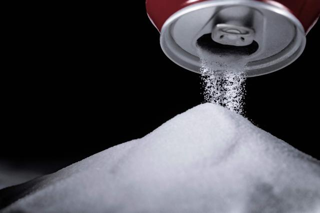 (FILES) This photograph taken on November 29, 2017 in Paris shows sugar grains being poured from a soft drink can. The German Federal Chancellery is blocking the Finance Ministry’s draft for a planned sugar tax. The proposal from the Finance Ministry is "not capable of winning a majority in the government in its current form," government sources said on October 1, 2026. (Photo by JOEL SAGET / AFP)