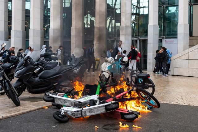 This photograph shows burning e-scooters near the Saint-Charles secondary school amid high school and student protests, in Marseille, southern France, on October 1, 2026. Since late September, students have staged protests outside schools over grievances ranging from timetables, class sizes and a shortage of teachers to overheated classrooms during this year's heatwaves. The protests started in the Ile-de-France region around Paris but have now spread to other cities nationwide. (Photo by Miguel MEDINA / AFP)