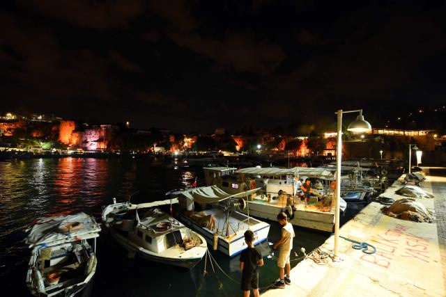 Children walk next to boats at Kaleici port on September 30, 2026 in Antalya, where the 2026 United Nations Climate Change Conference (COP31) will be held in Antalya. Turkey will host the COP31 climate talks from November 9 till 20 in the Mediterranean resort of Antalya. (Photo by Goksel YAPAR / AFP)