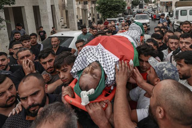 EDITORS NOTE: Graphic content / Relatives carry the body of Palestinian Mashhour Yassin, 51, at the Salfit Hospital in Salfit in the Israeli-occupied West Bank on October 1, 2026, after he was shot dead by Israeli settlers during a raid on the village of Yasuf southwest of Nablus, according to the mayor and the Palestinian health ministry. The raid came as international criticism mounts over surging levels of settler violence against Palestinians in the territory, which Israeli Prime Minister Benjamin Netanyahu downplayed last week. Israel's military told AFP it was looking into the details of the attack. (Photo by JAAFAR ASHTIYEH / AFP)