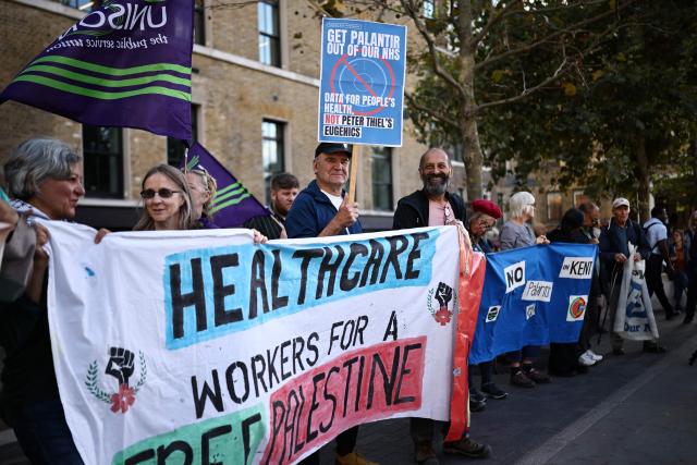 People take part in a protest against the US tech company Palantir, in Whitechapel, central London on October 1, 2026, to urge the British government to use a break clause that would prevent a contract between the AI giant and the National Health Service (NHS) being renewed beyond March 2027. The UK government is facing mounting pressure to end a £330-million (438 million USD) contract between the NHS and Palantir, as doctors, lawmakers and campaigners warn of ethical risks. (Photo by Henry NICHOLLS / AFP)