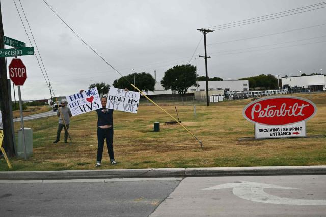 A protestor holds signs as the motorcade of US President Donald Trump drives by near Dallas Fort Worth International Airport in Dallas, Texas, on October 1, 2026. Trump is travelling to Texas and Oklahoma to speak at campaign rallies. (Photo by Kent NISHIMURA / AFP)