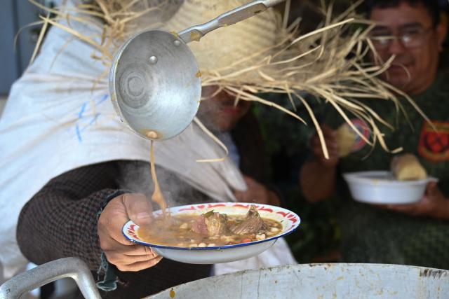 A person wearing a Karai Octubre costume holds a Jopara traditional meat soup on Karai Octubre day at the central market in Asuncion on October 1, 2026. (Photo by DANIEL DUARTE / AFP)