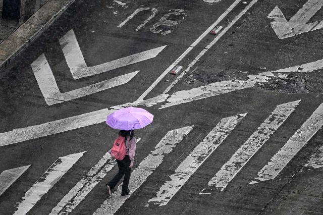 A pedestrian carrying an umbrella crosses a street in the rain in Mexico City on October 1, 2026. (Photo by Yuri CORTEZ / AFP)