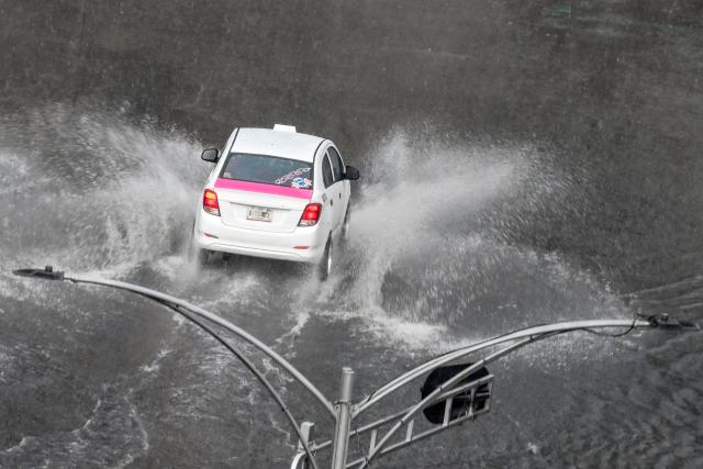 A taxi drives through a flooded street during heavy rainfall in Mexico City on October 1, 2026. (Photo by Yuri CORTEZ / AFP)