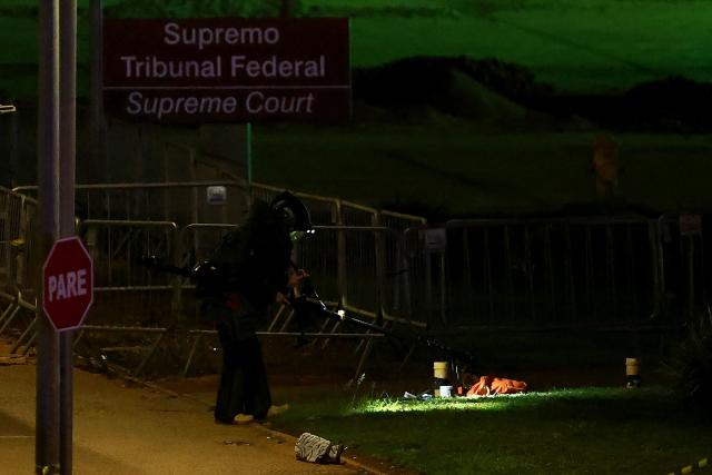 A Brazilian police officer inspects a possible bomb in a backpack outside the Supreme Court headquarters in Brasilia on October 1, 2026. Brazilian police are investigating a possible bomb placed in a backpack thrown outside the Supreme Court, the country's highest tribunal reported on October 1, 2026, three days before presidential elections begin. (Photo by Sergio LIMA / AFP)