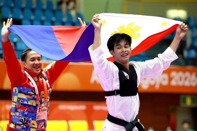 Jeus Gabriel Derick Yape (R) of the Philippines celebrates with his coach after winning the gold medal in the mixed individual virtual taekwondo competition during the 2026 Asian Games at the Toyohashi Gymnasium in Toyohashi on October 2, 2026. (Photo by DAVID GRAY / AFP)
