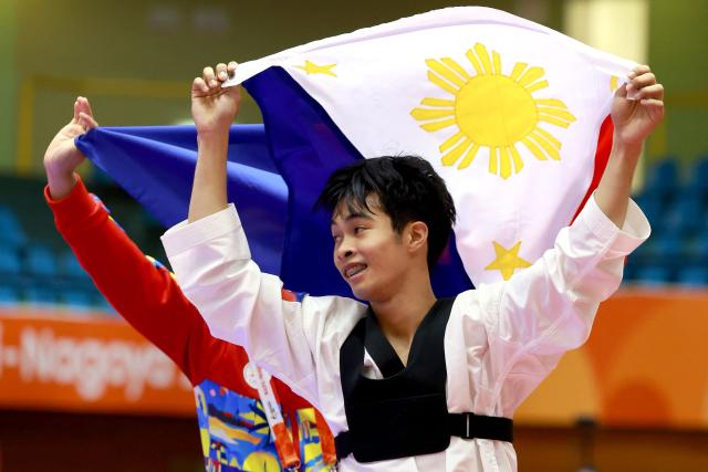 Jeus Gabriel Derick Yape (R) of the Philippines celebrates with his coach after winning the gold medal in the mixed individual virtual taekwondo competition during the 2026 Asian Games at the Toyohashi Gymnasium in Toyohashi on October 2, 2026. (Photo by DAVID GRAY / AFP)
