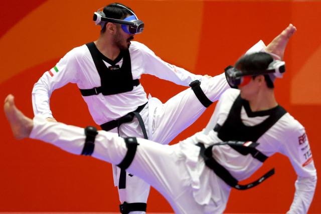 Iran’s Amirsina Bakhtiari (L) competes against Uzbekistan’s Jasurbek Jaysunov in the mixed individual virtual taekwondo round 16 during the 2026 Asian Games at the Toyohashi Gymnasium in Toyohashi on October 2, 2026. (Photo by DAVID GRAY / AFP)