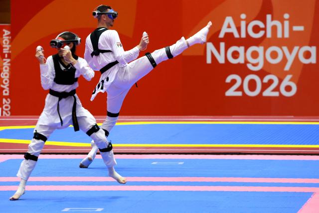 Kazakhstan’s Rita Bakisheva (L) competes against Jordan’s Mohammad Aladarbi in the mixed individual virtual taekwondo competition during the 2026 Asian Games at the Toyohashi Gymnasium in Toyohashi on October 2, 2026. (Photo by DAVID GRAY / AFP)