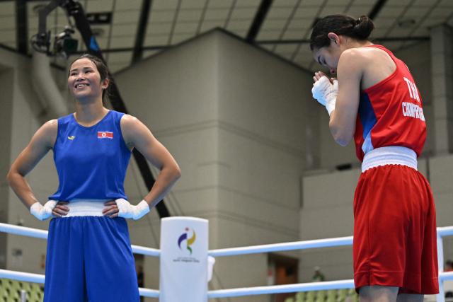 Thailand's Natnicha Chongprongklang (red) gestures next to North Korea's Pang Chol Mi after winning the women's 54kg gold medal boxing bout during the 2026 Asian Games at Nishio Gymnasium in Nishio on October 2, 2026. (Photo by MOHD RASFAN / AFP)