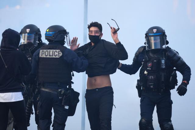 Police officers hold a protestor amid tear gas as protesting students carry out blockading action near the Kerichen high school in Brest, western France, on October 2, 2026. Since late September, students have staged protests outside schools over grievances ranging from timetables, class sizes and a shortage of teachers to overheated classrooms during this year's heatwaves. The protests started in the Ile-de-France region around Paris but have now spread to other cities nationwide. (Photo by FRED TANNEAU / AFP)
