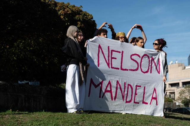Students of Mandela's high school make heart shape with their hands as they gather after a fire destroys the entrance of their school as protesting students carry out blockading action in Nantes, western France, on October 2, 2026. Since late September, students have staged protests outside schools over grievances ranging from timetables, class sizes and a shortage of teachers to overheated classrooms during this year's heatwaves. The protests started in the Ile-de-France region around Paris but have now spread to other cities nationwide. (Photo by Sebastien Salom-Gomis / AFP)