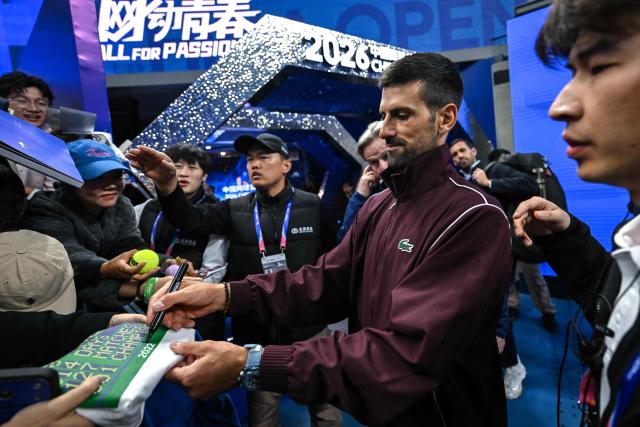 Serbia's Novak Djokovic (2R) signs autographs after his victory against China's Bu Yunchaokete in their men's singles match at the China Open tennis tournament in Beijing on October 2, 2026. (Photo by Pedro PARDO / AFP)