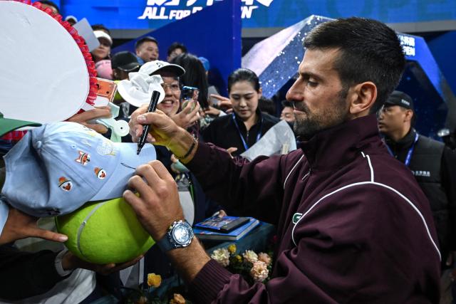 Serbia's Novak Djokovic (R) signs autographs after his victory against China's Bu Yunchaokete in their men's singles match at the China Open tennis tournament in Beijing on October 2, 2026. (Photo by Pedro PARDO / AFP)