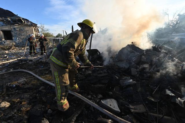 Firefighters extinguish a fire at a house following air strikes in Kharkiv on October 2, 2026, amid the Russian invasion of Ukraine. (Photo by SERGEY BOBOK / AFP)
