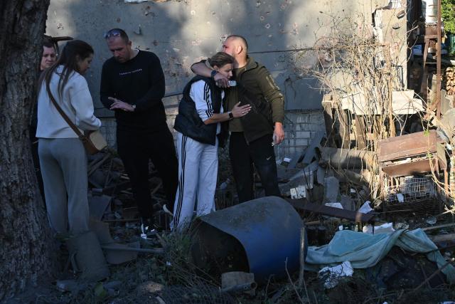 EDITORS NOTE: Graphic content / A couple mourn as they stand next to the body of a relative killed following air strikes in Kharkiv on October 2, 2026, amid the Russian invasion of Ukraine. (Photo by SERGEY BOBOK / AFP)