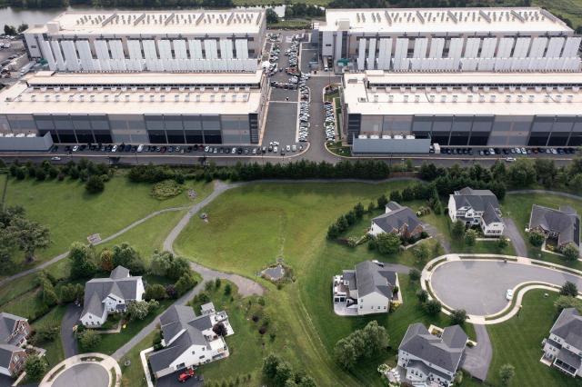 (FILES) This aerial view shows an Amazon Web Services (AWS) data center adjacent to single-family homes in Stone Ridge, Virginia on August 12, 2026. Amazon on October 2, 2026, pledged more than $1 billion over five years for US communities that host its data centers, the latest tech giant seeking to win over residents increasingly hostile to the AI-fueled construction boom. The "Built Together" program, unveiled by Amazon Web Services chief Matt Garman in a 3,000-word blog post, will fund free community college degrees and trades training as well as energy-efficiency upgrades for schools and homes. (Photo by Brendan Smialowski / AFP)