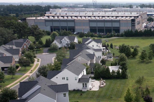 (FILES) This aerial view shows an Amazon Web Services (AWS) data center adjacent to single-family homes in Stone Ridge, Virginia on August 12, 2026. Amazon on October 2, 2026, pledged more than $1 billion over five years for US communities that host its data centers, the latest tech giant seeking to win over residents increasingly hostile to the AI-fueled construction boom. The "Built Together" program, unveiled by Amazon Web Services chief Matt Garman in a 3,000-word blog post, will fund free community college degrees and trades training as well as energy-efficiency upgrades for schools and homes. (Photo by Brendan Smialowski / AFP)