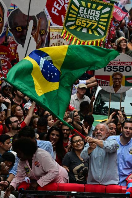 Brazil's President and presidential candidate Luiz Inacio Lula da Silva waves a nationall flag during a campaign walk through downtown Rio de Janeiro, Brazil, on October 2, 2026. Next October 4 Lula da Silva 80, faces off against the 45-year-old right-wing senator Flavio Bolsonaro, who is trying to ride the regional conservative wave encouraged by US President Donald Trump. (Photo by Pablo PORCIUNCULA / AFP)