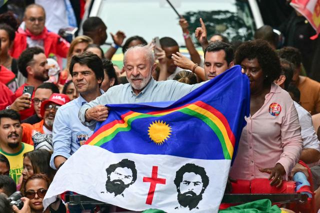 Brazil's President and presidential candidate Luiz Inacio Lula da Silva (C) holds a flag next to candidates for the Federal Senate Benedita da Silva (PT) and Pedro Paulo (PSD) during a campaign walk through downtown Rio de Janeiro, Brazil, on October 2, 2026. Next October 4 Lula da Silva 80, faces off against the 45-year-old right-wing senator Flavio Bolsonaro, who is trying to ride the regional conservative wave encouraged by US President Donald Trump. (Photo by Pablo PORCIUNCULA / AFP)