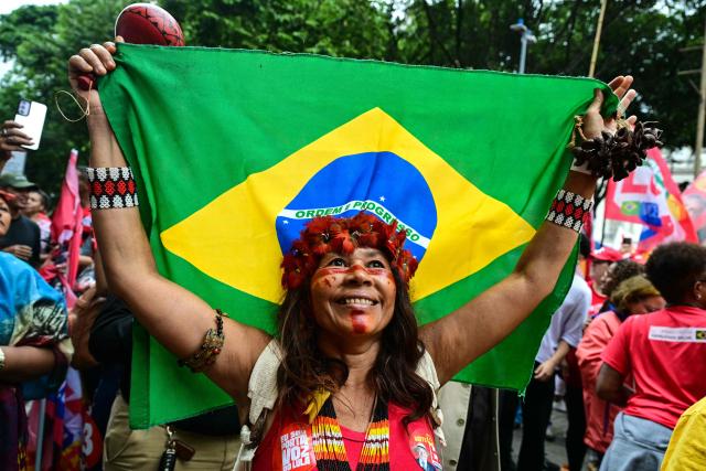 A woman  Indigenous supporter of Brazil's President and presidential candidate Luiz Inácio Lula da Silva  holding a national  flag during a campaign walk through downtown Rio de Janeiro, Brazil on October 2, 2026. Next October 4 Lula da Silva 80, faces off against the 45-year-old right-wing senator Flavio Bolsonaro, who is trying to ride the regional conservative wave encouraged by US President Donald Trump. (Photo by Pablo PORCIUNCULA / AFP)