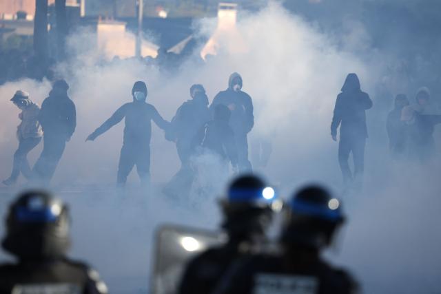 French police officers operate in the foreground as demonstrators stand amid tear gas during student protests near the Kerichen high school in Brest, western France, on October 2, 2026. New clashes erupted nationwide between French high school students and police in an escalating protest movement demanding better conditions in education. (Photo by Fred TANNEAU / AFP)