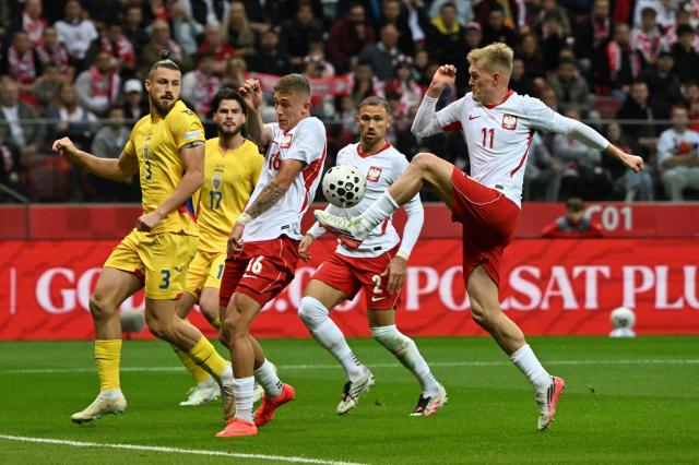 Poland's forward #11 Karol Swiderski (R) kicks the ball past Poland's midfielder #03 Norbert Wojtuszek (L), Romania's midfielder #17 Tudor Baluta (2nd L) and Poland's defender #02 Matthew Cash (2nd R) during the UEFA Nations League Group B4 football match between Poland and Romania at the National Stadium in Warsaw on October 2, 2026. (Photo by Sergei GAPON / AFP)