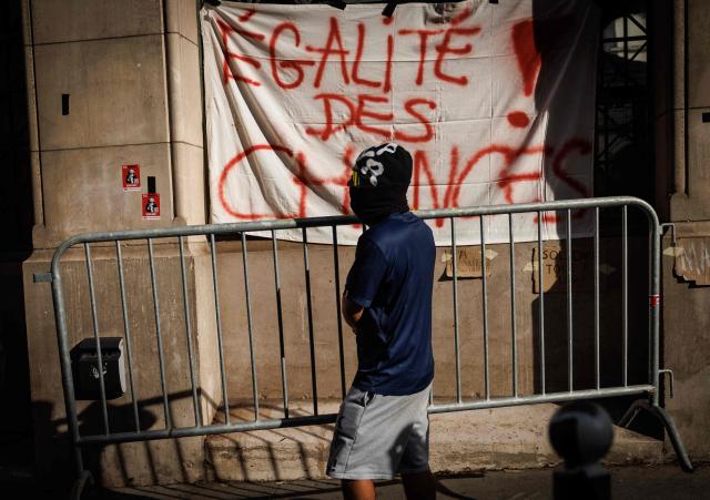 A student carries a barrier in front of the Louis-le-Grand high school in central Paris, on October 2, 2026. Since late September, students have staged protests outside schools over grievances ranging from timetables, class sizes and a shortage of teachers to overheated classrooms during this year's heatwaves. The protests started in the Ile-de-France region around Paris but have now spread to other cities nationwide. (Photo by Simon WOHLFAHRT / AFP)