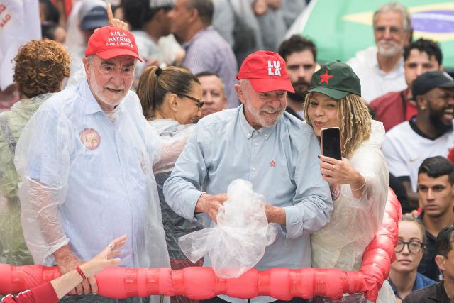 Brazil's President and presidential candidate Luiz Inacio Lula da Silva (C) smiles for a selfie with former federal deputy Aurea Carolina (R) and federal deputy Patrus Ananias (L) during a campaign rally in Belo Horizonte, Minas Gerais state, Brazil on October 2, 2026. Brazilians go to the polls on October 4, 2026, in a tight race led by leftist President Luiz Inacio Lula da Silva and right-wing senator Flavio Bolsonaro, son of former president Jair Bolsonaro. (Photo by Gledston Tavares / AFP)