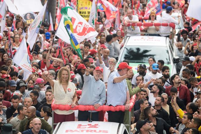 Brazil's President and presidential candidate Luiz Inacio Lula da Silva (C) waves a national flag next to former federal deputy Aurea Carolina (L) and federal deputy Patrus Ananias (R) during a campaign rally in Belo Horizonte, Minas Gerais state, Brazil on October 2, 2026. Brazilians go to the polls on October 4, 2026, in a tight race led by leftist President Luiz Inacio Lula da Silva and right-wing senator Flavio Bolsonaro, son of former president Jair Bolsonaro. (Photo by Gledston Tavares / AFP)